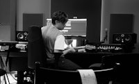 a man playing guitar in a recording studio